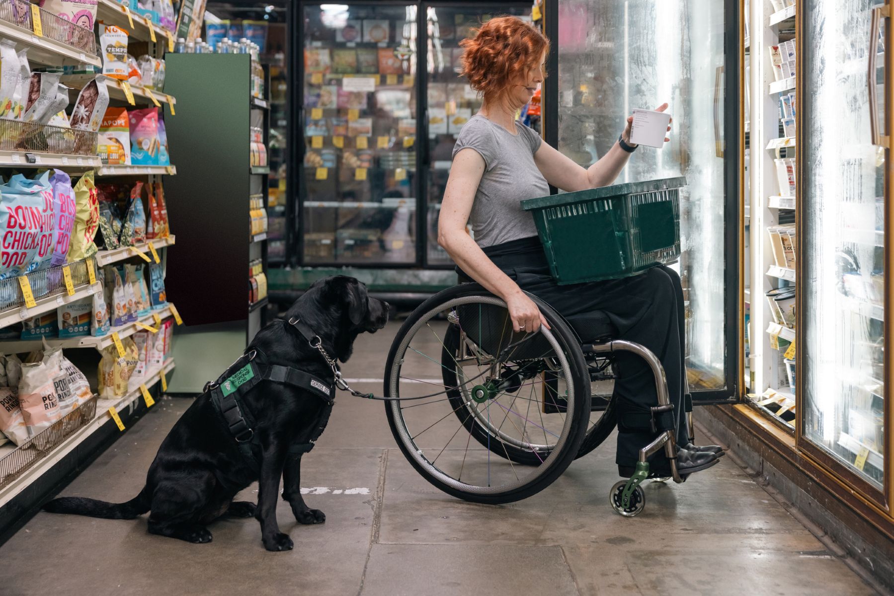 Una mujer en silla de ruedas va de compras con su perro de servicio.