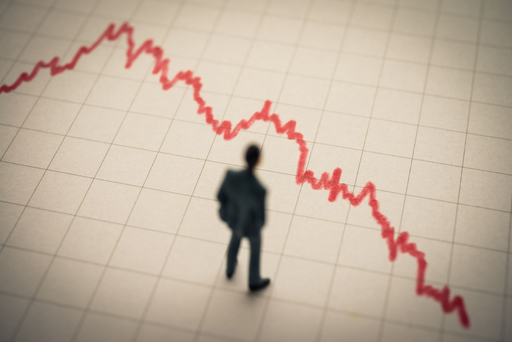 Silueta de hombre de negocios sobre un gráfico en tendencia descendente.