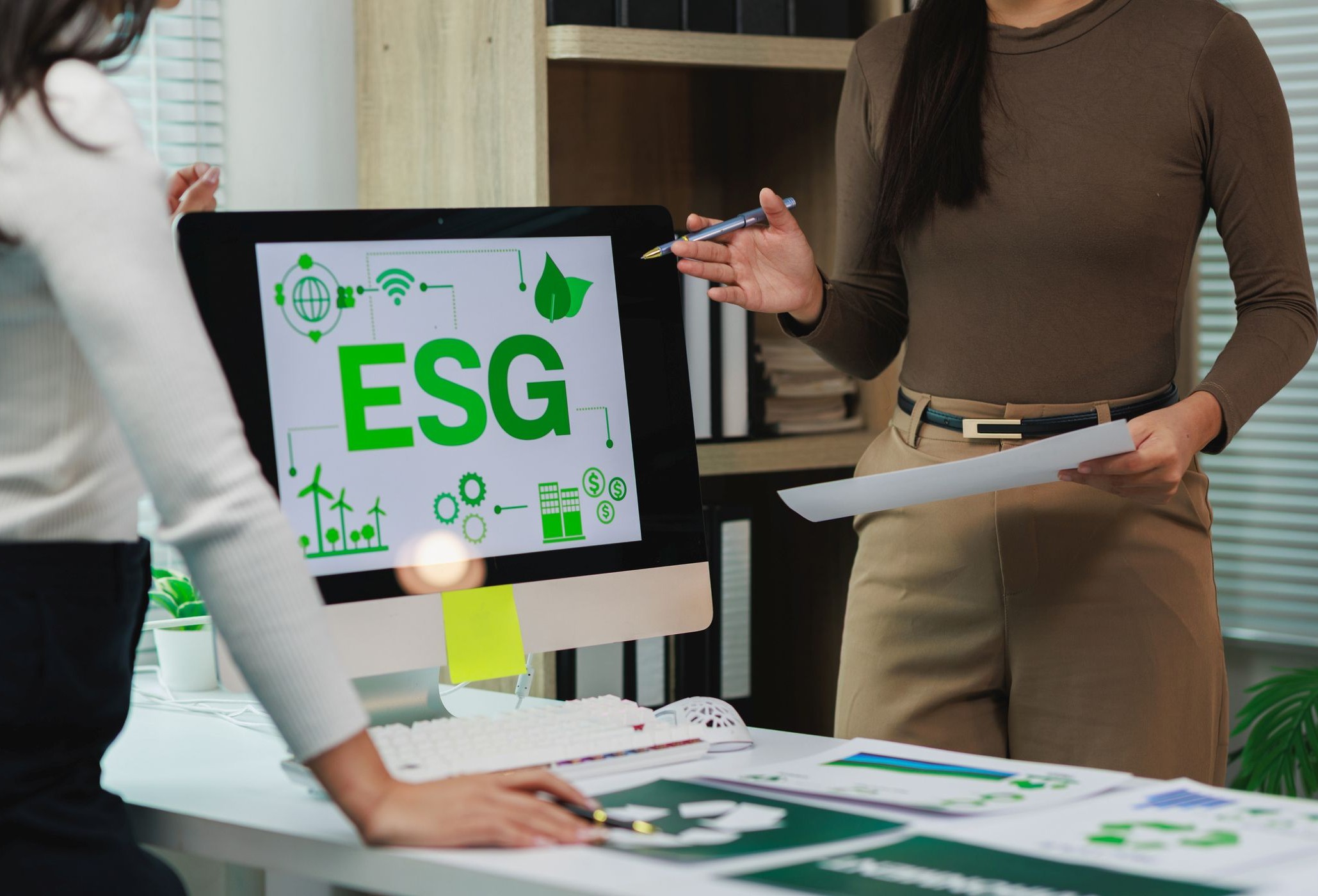 Mujeres directivas discuten la estrategia de sostenibilidad delante de una mesa con una pantalla de ordenador